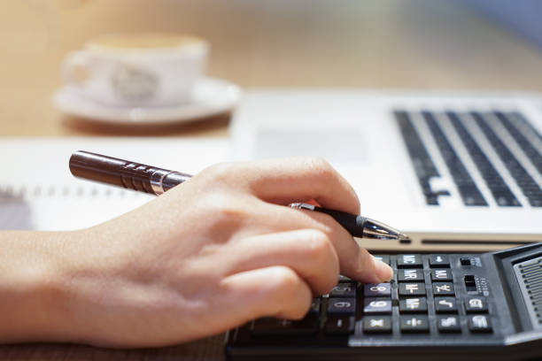 Bookkeeper working on a laptop with a calculator and financial documents