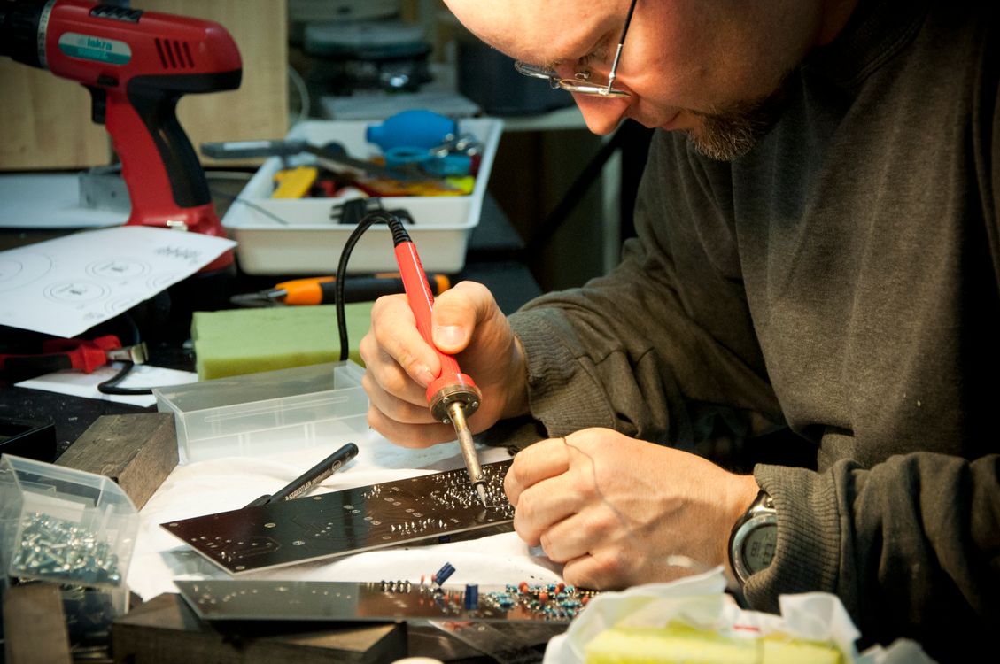 Technician soldering a circuit board at a workbench
