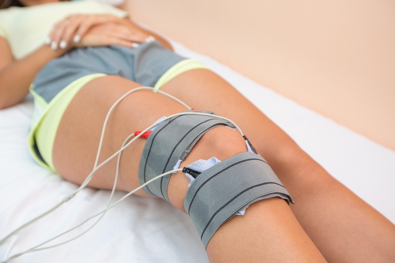 Physical therapy provider using electrical stimulation equipment during a knee treatment