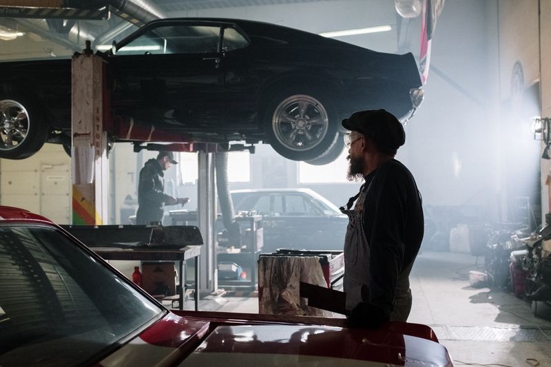 Mechanics working on a lifted vehicle in an auto repair garage